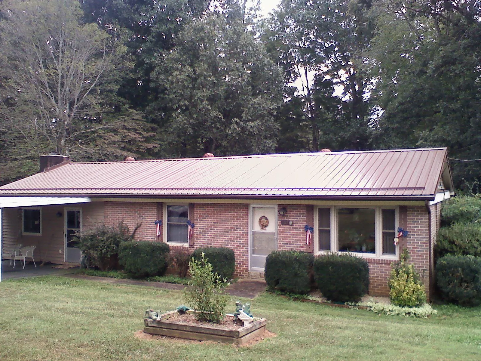 Bronze metal roof on a brick ranch home with a carport in Jackson