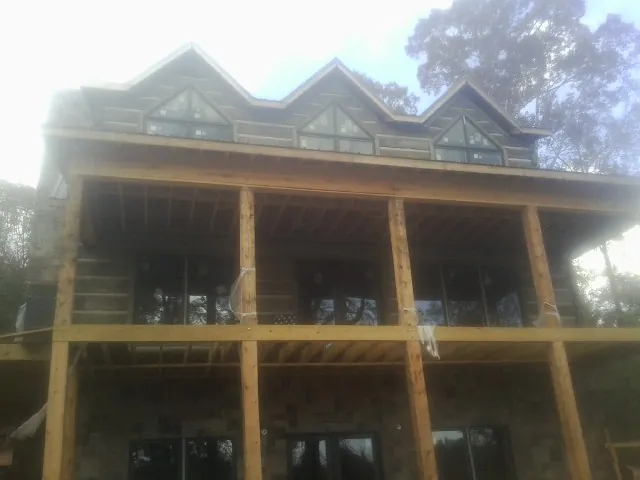 Dormers and porch framing on a large log home under construction — Roof Coating work by our crew in Jackson